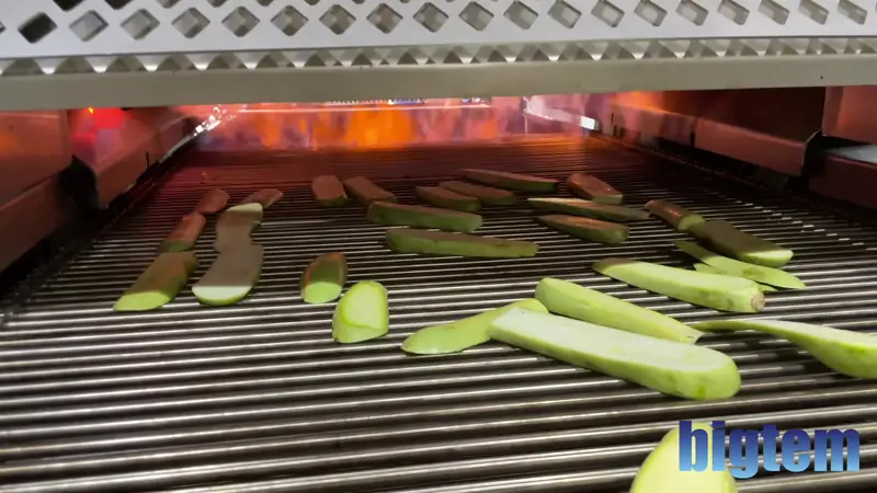 Zucchini slices on the heated rod conveyor of a Bigtem grill marker